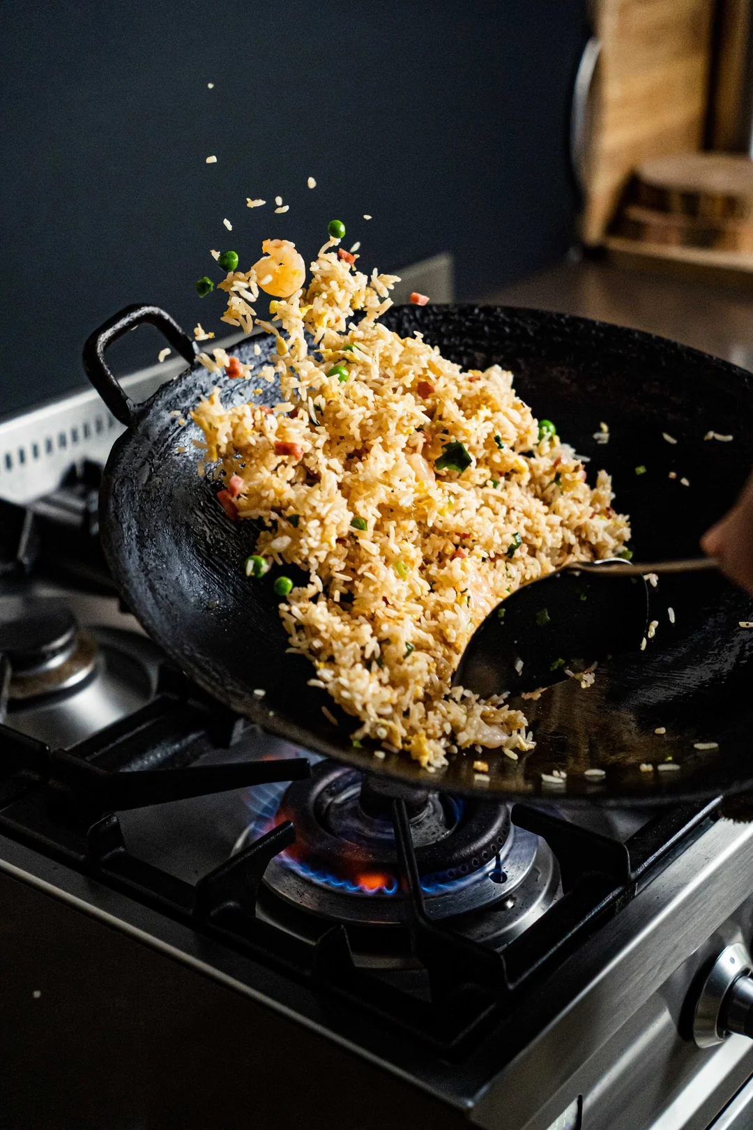 Wok hei fried rice being tossed in a sizzling wok over an open flame.