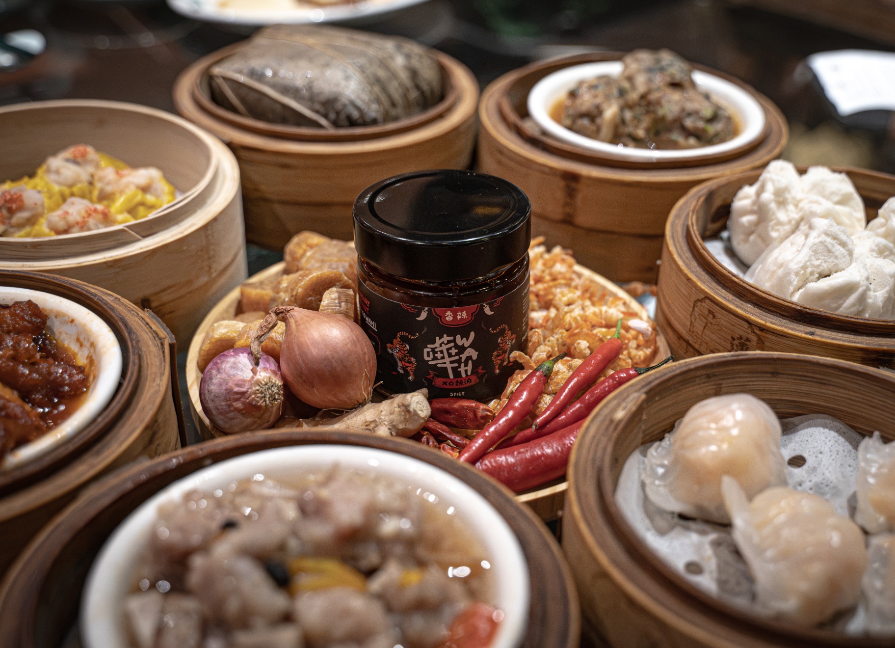 WAH XO Chilli Oil jar surrounded by dim sum and fresh ingredients.